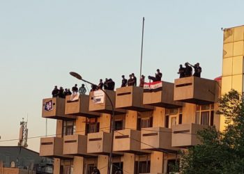 متظاهرون يعتلون على بناية قريبة من الخضراء تقليداً للمطعم التركي